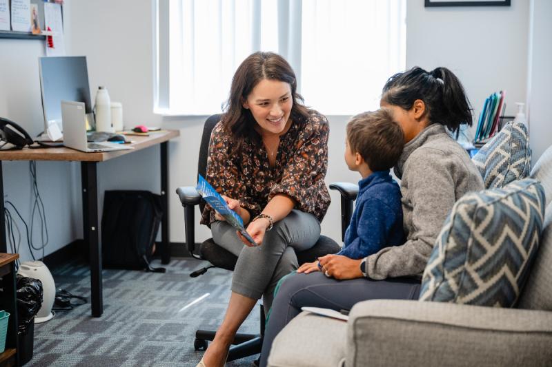 a woman talking to a mother and child on her lap
