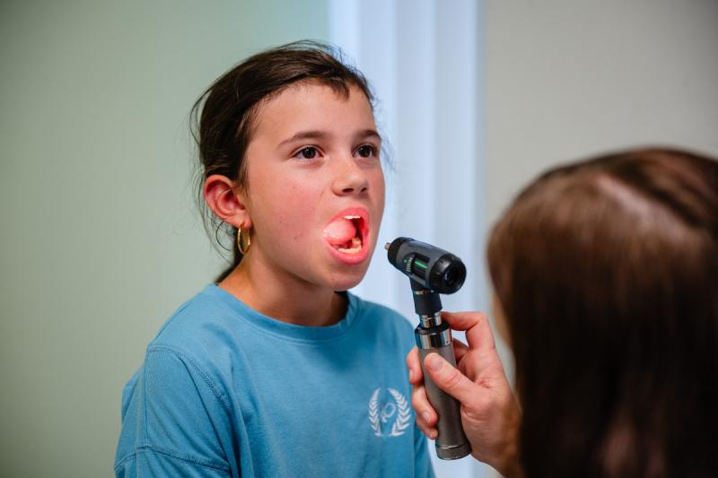 a girl getting her tonsils checked out by a pediatrician